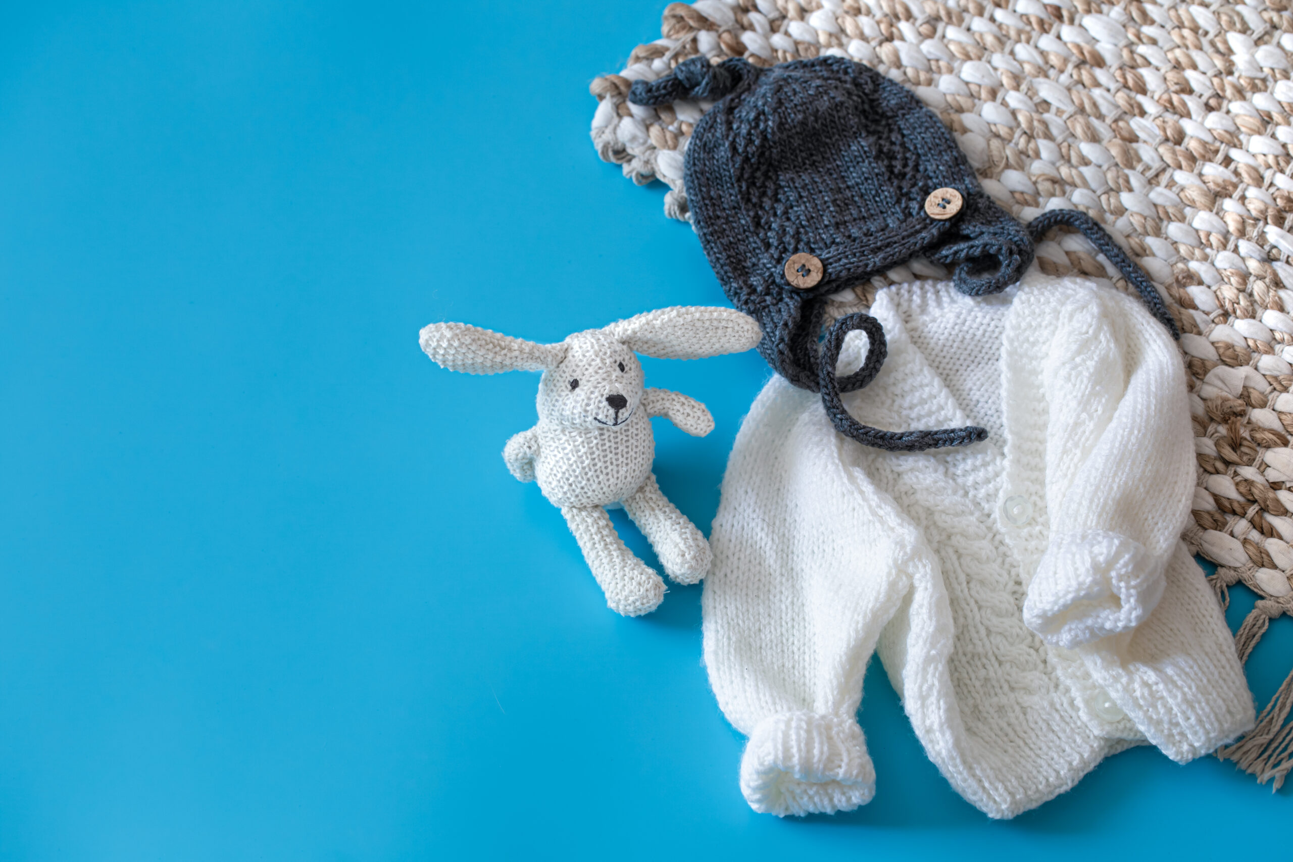Knitted baby clothes and accessories on a blue background .